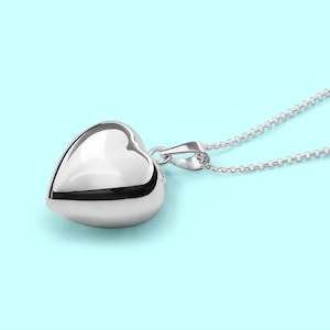 May include: A silver heart-shaped pendant necklace with a delicate chain. The pendant is smooth and shiny, reflecting light.