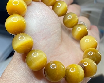 May include: A golden tiger's eye gemstone bracelet with round beads. The bracelet is made of natural stones and has a polished finish.