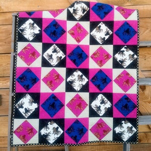 May include: A pink, blue, white, and black quilt with a repeating pattern of stylized octopuses. The quilt is made of fabric squares sewn together in a checkerboard pattern.