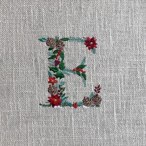 Diseño de bordado de la letra E navideña: monograma del alfabeto con piñas, flores y nieve / Fuente festiva