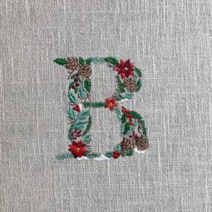 Diseño de bordado de la letra B navideña: monograma del alfabeto con piñas, flores y nieve / Fuente festiva
