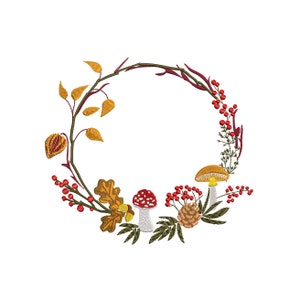 Op de afbeelding: Geborduurde herfstkrans met herfstbladeren, paddenstoelen, bessen en een dennenappel. De cirkelvormige krans gebruikt herfstkleuren zoals goud, rood, bruin en groen. Het ontwerp is gedetailleerd en lijkt met de hand geborduurd.