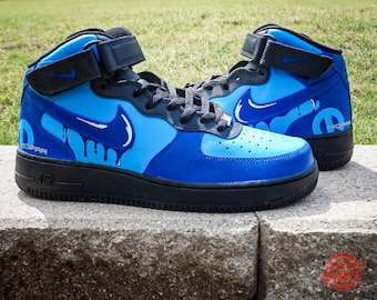 May include: Blue and white custom-designed high-top sneakers with a black swoosh logo and the word "MOPAR" on the side.