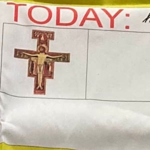 Può includere: Un cartoncino bianco con la parola "TODAY" in lettere rosse. In alto a sinistra c'è una piccola immagine di un crocifisso con una persona sopra.