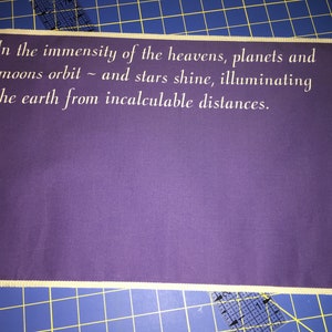 May include: A purple fabric banner with white text that reads "In the immensity of the heavens, planets and moons orbit ~ and stars shine, illuminating the earth from incalculable distances."