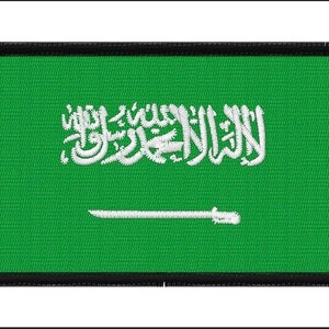 Puede incluir: Un parche bordado con la bandera de Arabia Saudita. La bandera es verde con una inscripción árabe blanca y una espada blanca.