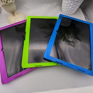 May include: Three tablet cases in different colours: purple, green and blue. Each case has a black screen protector and a textured finish.