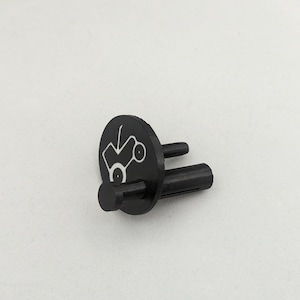 May include: Black plastic part with a white logo and two prongs. The logo is a stylised design of a car with wheels.