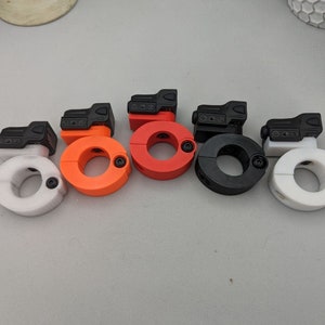 May include: Five different coloured plastic mounts for attaching a flashlight or other accessory to a rail system. The mounts are in white, orange, red, black, and white.