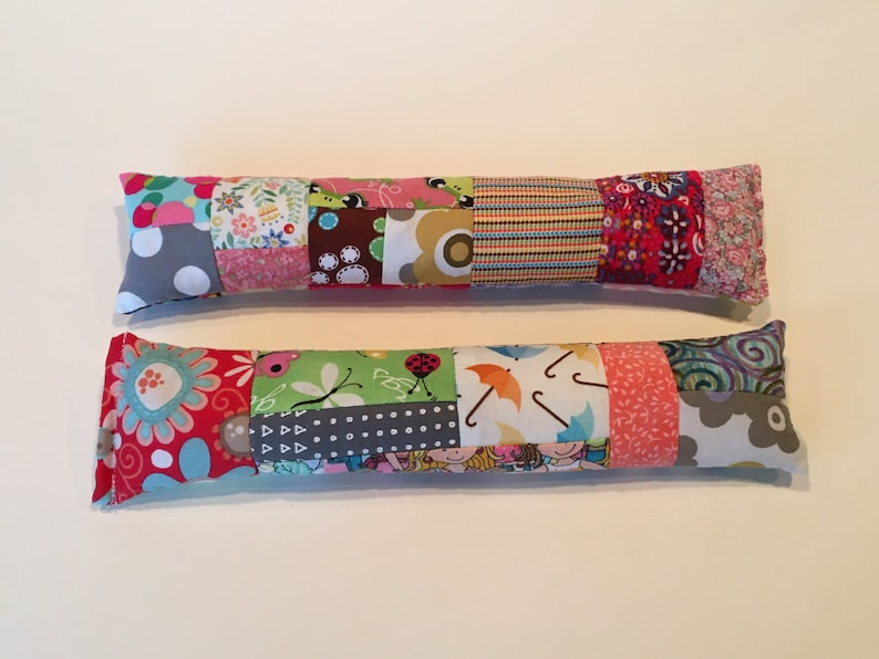 May include: Two colorful patchwork fabric catnip toys. The toys are long and rectangular, with a variety of patterns and colors, including red, pink, green, blue, and gray.
