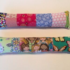 May include: Two colorful fabric pillows with different patterns. The top pillow has a patchwork design with pink, red, blue, and white fabrics. The bottom pillow has a green fabric with a butterfly pattern and a fabric with a pattern of girls.