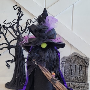 Peut inclure: Un gnome de sorci&egrave;re noir portant un chapeau violet, une cape noire et tenant un balai. Le gnome a un nez vert et se tient devant une pierre tombale sur laquelle est inscrit "RIP".
