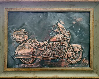 May include: A copper-colored motorcycle sculpture framed in a green wood frame. The motorcycle is detailed with a saddle, handlebars, and a luggage rack. The sculpture is signed "2020".