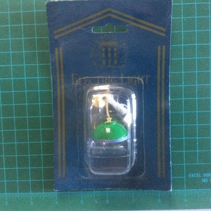 Peut inclure: Une miniature de luminaire électrique vert et blanc avec une base dorée, emballée sur une carte bleue avec le texte "Excel Hobby Blades No. 50002".