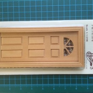 May include: A wooden dollhouse door with a decorative windowpane. The door is 7.6 cm wide and 19.3 cm tall. The door is made by Houseworks and is part of their Carolina Door collection. The product number is #6023.