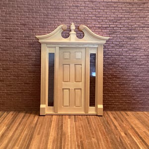 May include: A wooden door with a decorative top and six panels. The door is set in a brick wall and has a wood frame.