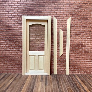 Peut inclure: Une petite porte en bois avec un panneau de verre transparent et un petit panneau en bas. Le cadre de la porte et les garnitures sont en bois de couleur claire. L'arrière-plan présente un mur de briques et un sol en bois.
