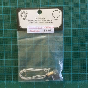 May include: A small, silver, swivel spotlight bulb with 30 cm of white wire. The packaging includes the product number CK1010-10, the price £6.95, and the text "Miniatures MAE Électricité".