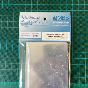 May include: A package containing two 3.4 by 12 inch mirror sheets for model building. The package is labelled "Mirror Sheet 2pc 3.4x12" #MGT-1( ) Remove protective film for the ultimate shine."