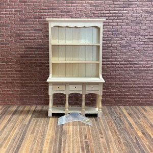 Vintage style open top sideboard. 1/12 Scale in unpainted wood. 2 shelves top, bottom with 3 drawers turned legs. Hardware included. 10902.