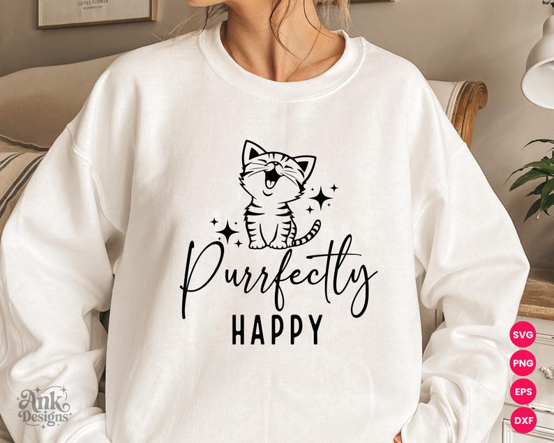 以下が含まれることがあります： 白いスウェットシャツ。黒いグラフィックで、笑顔の猫と「Purrfectly HAPPY」の文字が描かれています。デザインには星が含まれています。カジュアルで快適なスウェットシャツで、気まぐれな猫のデザインです。