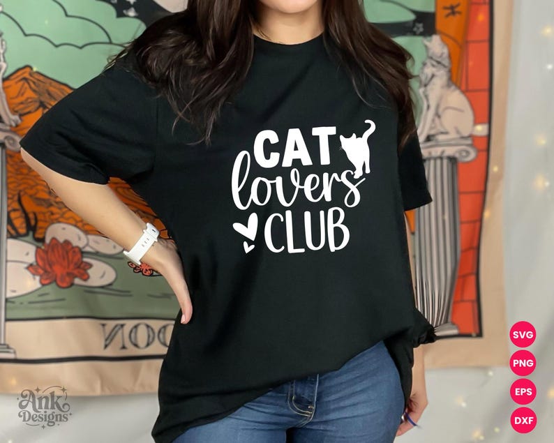 以下が含まれることがあります： 白い「CAT lovers CLUB」の文字と猫のシルエットが入った黒いTシャツ。猫好きにぴったりのカジュアルウェアです。