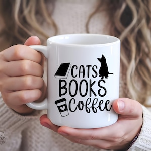 以下が含まれることがあります： 「CATS BOOKS Coffee」の文字と黒い猫のシルエットが描かれた白いセラミックマグカップ。本とコーヒーカップのグラフィックも特徴です。マグカップは人が持っています。