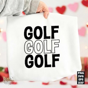 May include: A white tote bag with the word "GOLF" printed three times in a bold, black font. The bag is held up by a person. The background includes Valentine's Day decorations.