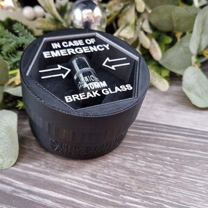 May include: A black hexagonal break glass alarm with a clear plastic cover and the text "IN CASE OF EMERGENCY TURN BREAK GLASS" printed on it.