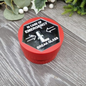 May include: Red break glass box with a clear plastic cover. The cover has the text "IN CASE OF EMERGENCY BREAK GLASS" and two arrows pointing in opposite directions. There is a small metal hammer inside the box.