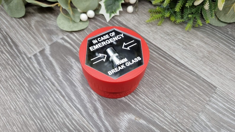 May include: Red break glass box with a clear plastic cover. The cover has the text "IN CASE OF EMERGENCY BREAK GLASS" and two arrows pointing in opposite directions. There is a small metal hammer inside the box.