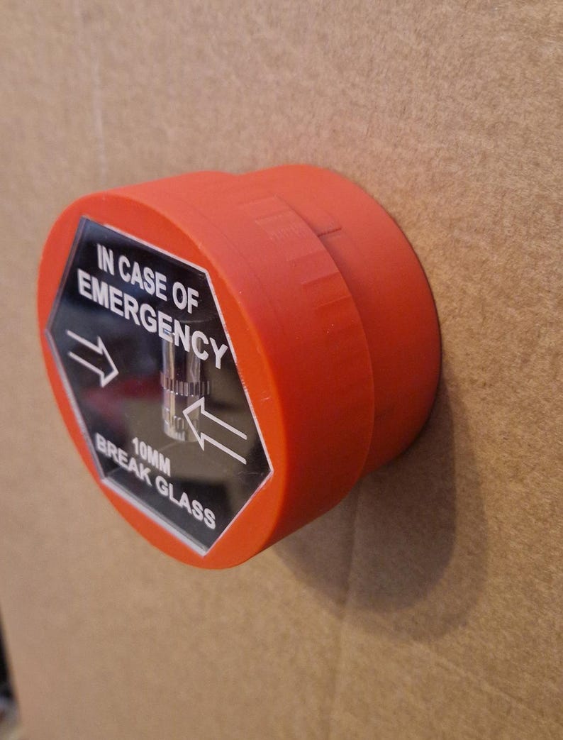 May include: Red break glass emergency alarm with a black hexagonal label that reads "IN CASE OF EMERGENCY 10MM BREAK GLASS" with arrows pointing to the left and right.