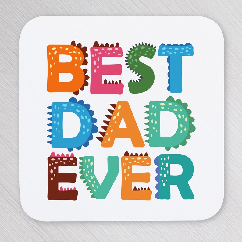 以下が含まれることがあります： 恐竜のようなデザインのカラフルなスタイリッシュな文字で「BEST DAD EVER」と書かれた白いコースターです。