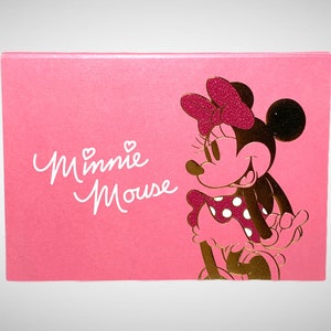 May include: Pink card with a gold foil image of Minnie Mouse. The card says "Minnie Mouse" in white script.
