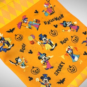 Puede incluir: Tela naranja con tem&aacute;tica de Halloween con Mickey Mouse y otros personajes de Disney. La tela tiene un patr&oacute;n repetitivo de calabazas, fantasmas, murci&eacute;lagos y las palabras "Boo!" y "Spooky".