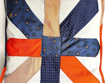 May include: A white pillow with a Union Jack design made from repurposed neckties. The pillow is made of different colored fabrics, including blue, orange, and gold.