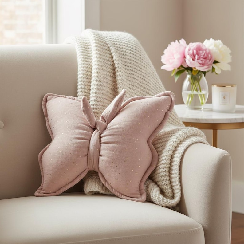 Pink butterfly decorative pillow on cream armchair, handmade nursery cushion for baby girl room, soft cotton butterfly kids decor