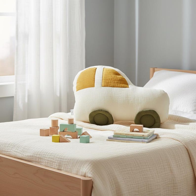 Green school bus shaped pillow with white windows and yellow wheels