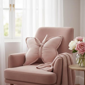Pink butterfly decorative pillow on cream armchair, handmade nursery cushion for baby girl room, soft cotton butterfly kids decor