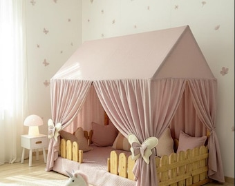 Op de afbeelding: Een roze hemelbed met een houten hekwerk-stijl hoofdbord en voetbord. Het bed is versierd met kussens en een pluchen eenhoornspeelgoed. De kamer heeft vlinder muurstickers en een rond tapijt.