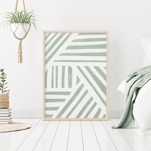 K&ouml;nnte beinhalten: Ein gerahmter abstrakter Druck mit einem geometrischen Muster aus wei&szlig;en Linien auf einem Salbeigr&uuml;n-Hintergrund. Der Druck h&auml;ngt an einer wei&szlig;en Wand &uuml;ber einem Bett mit wei&szlig;en Bettw&auml;sche und einer Salbeigr&uuml;n-Decke.