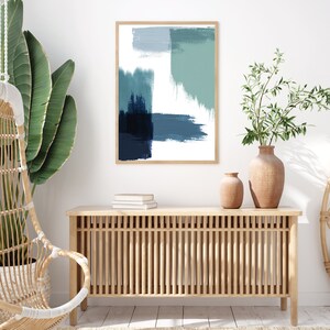 May include: A wooden console table with a slatted design and a framed abstract painting with blue and green brushstrokes hanging above it. Two potted plants are on the floor next to the table.