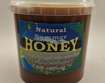 May include: A clear plastic tub filled with dark brown raw, unfiltered honey. The label features the text Natural Summer HONEY, Season 2026, and lists ingredients including buckwheat, rapeseed, sweetbrier, and cornflower blossoms. Net Weight 750g.