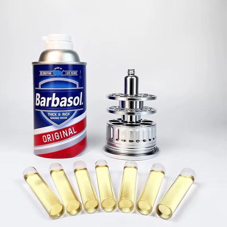May include: A can of Barbasol shaving cream with a blue and red label, a silver razor stand, and seven small glass vials filled with a yellow liquid. The shaving cream can reads "Original".