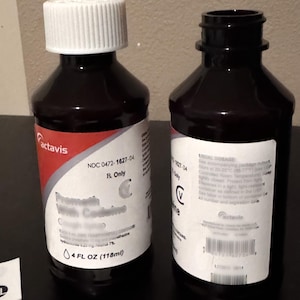 May include: Two Actavis brand medicine bottles. One bottle is sealed with a white cap, the other is open. Both bottles have white labels with red accents and black text. The labels include the text "Promethazine with Codeine" and "4 FL OZ (118ml)."