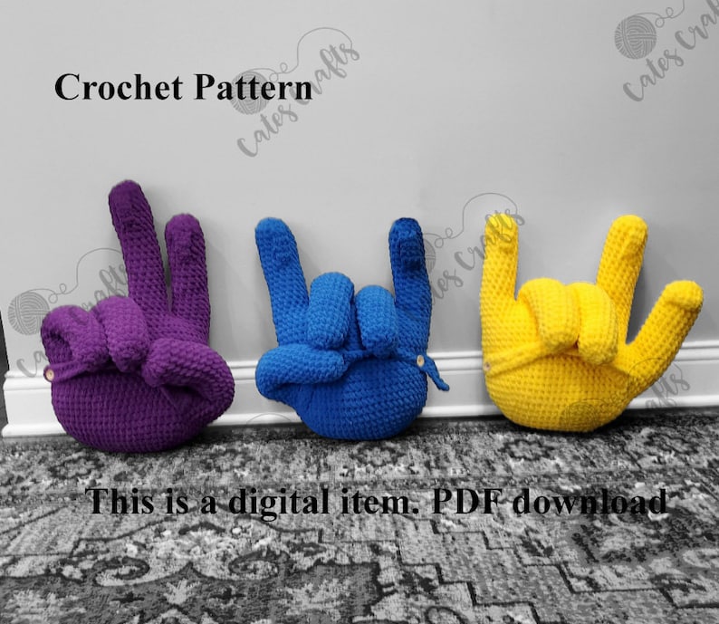 Pu&ograve; includere: Tre cuscini a forma di mano all'uncinetto in viola, blu e giallo. I cuscini sono a forma di segno di pace, gesto rock and roll e gesto ti amo. Modello all'uncinetto Cates Crafts.