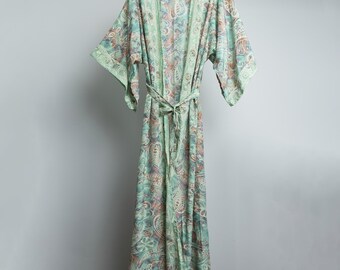 Op de afbeelding: Een lange, vloeiende kimono met een paisley patroon in groen, blauw en perziktinten. De kimono heeft wijde mouwen en een bijpassende ceintuur. Het hangt aan een witte hanger tegen een effen achtergrond.