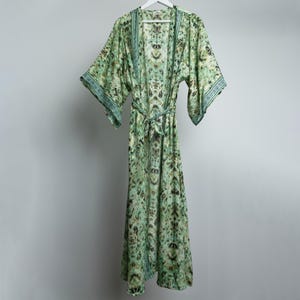 Op de afbeelding: Een lange groene en blauwe geprinte robe met een strikceintuur. De robe heeft een V-hals en lange mouwen.