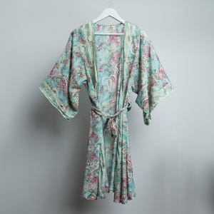 May include: A light blue and pink paisley patterned robe with a tie belt.
