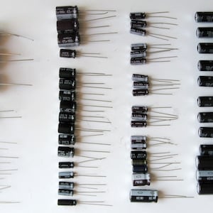 Può includere: Assortimento di condensatori di varie dimensioni e colori, tra cui nero, marrone e blu. Alcuni condensatori hanno testo stampato, come "47uF 40V" e "220uF 25V".